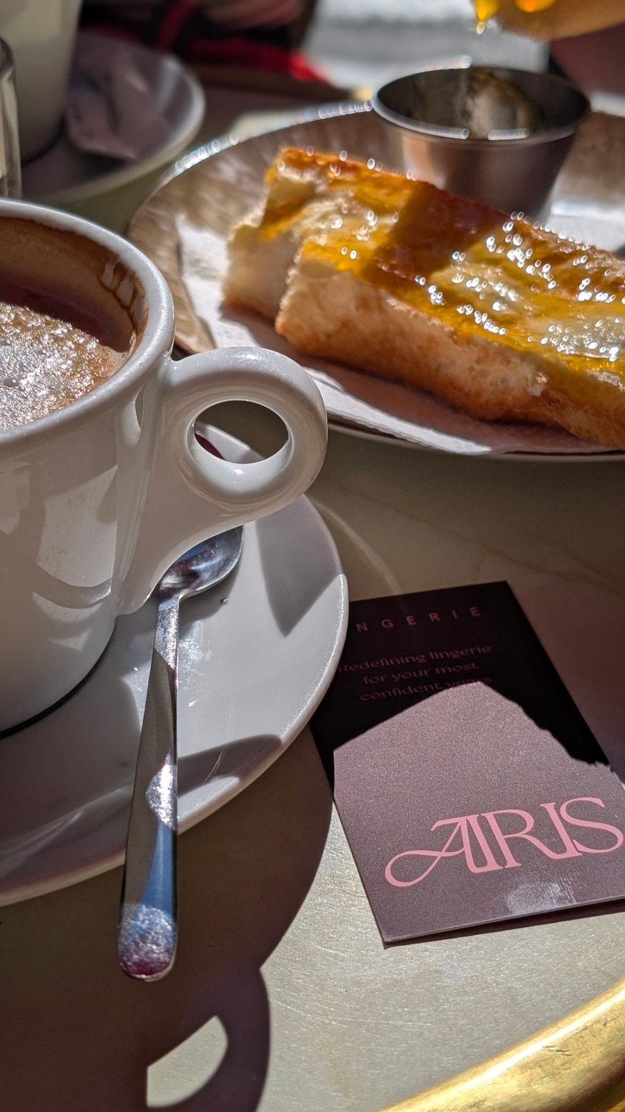 An Airis card on a gold café table beside a coffee cup and toast in Paris